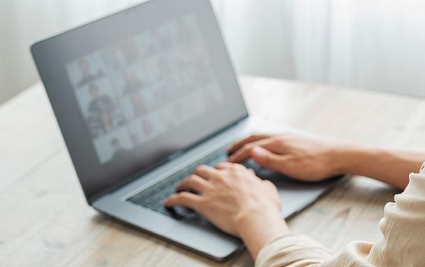 Hände auf einer Laptop-Tastatur, Videokonferenz